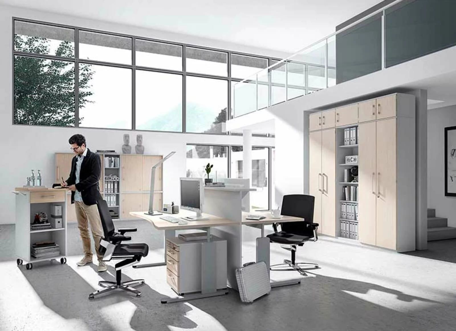 Offenes Büro mit höhenverstellbaren Schreibtischen, Bürostühlen und hellen Aktenschränken, ein Mann arbeitet im Stehen