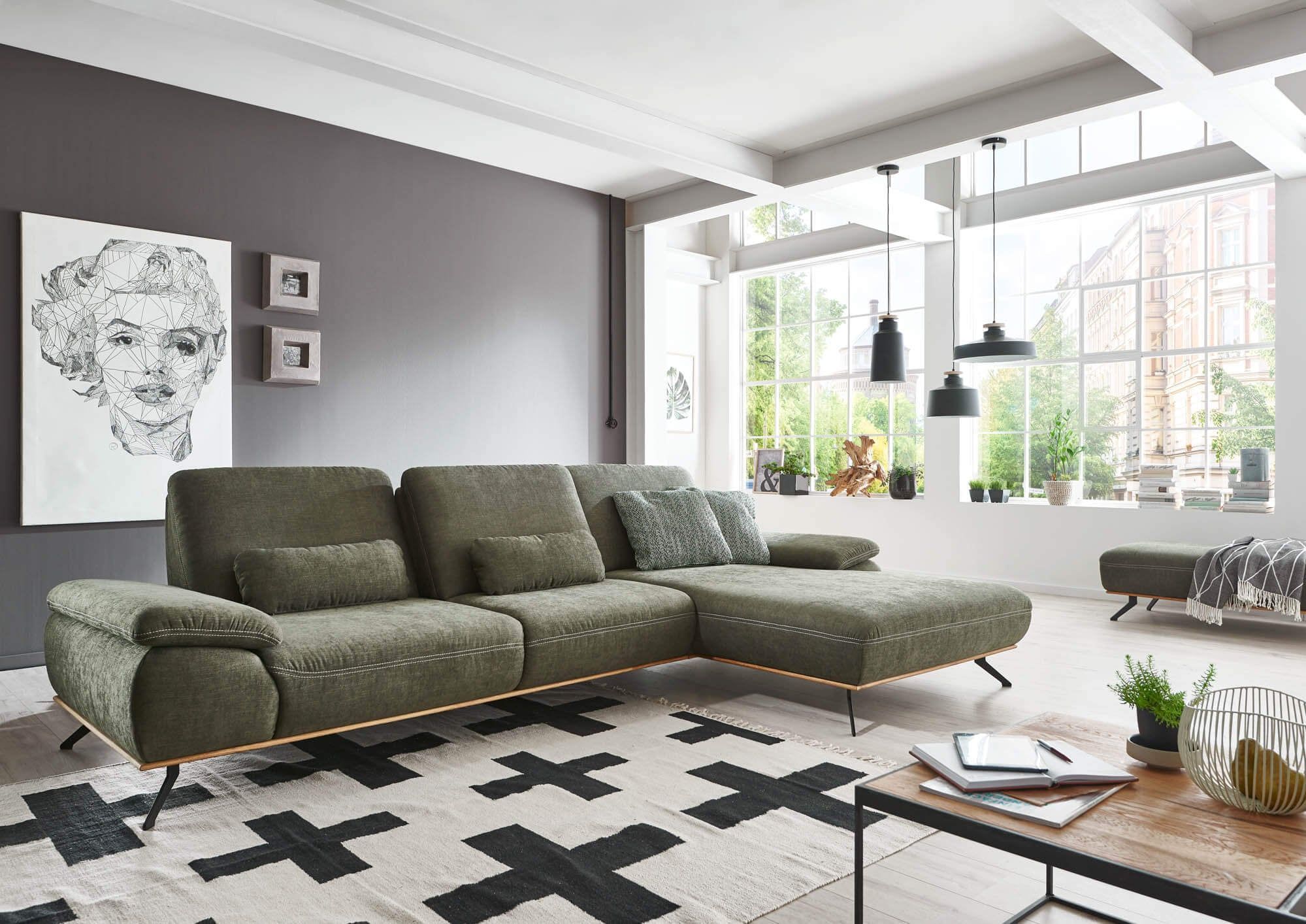 Ecksofa in Olivgrün mit Holzfüßen in einem hellen Loft