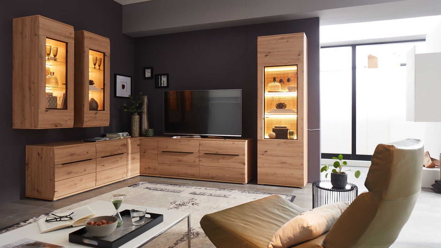 Wohnzimmer mit Eiche-Wohnwand, beleuchteten Vitrinen und Relaxsessel